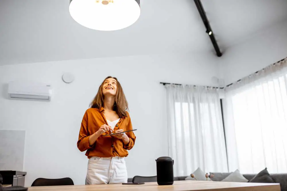 Young woman controlling the home light with a smart home in the living room. 