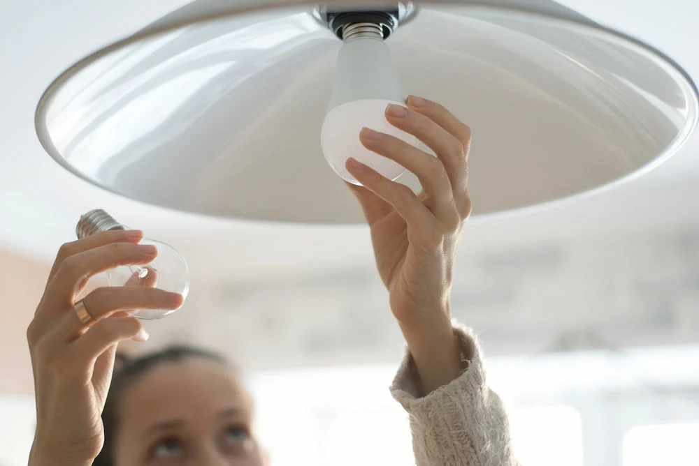 A woman replacing an incandescent bulb with a power-efficient LED