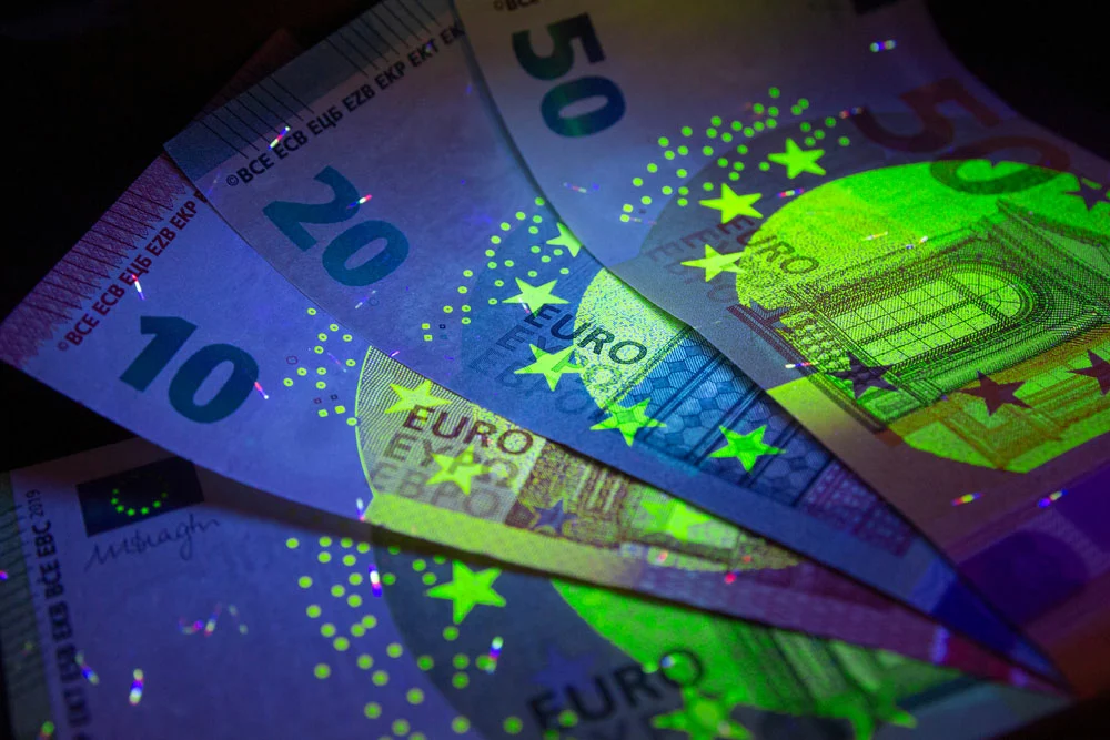 The security features in Euro currency fluorescing under UV light