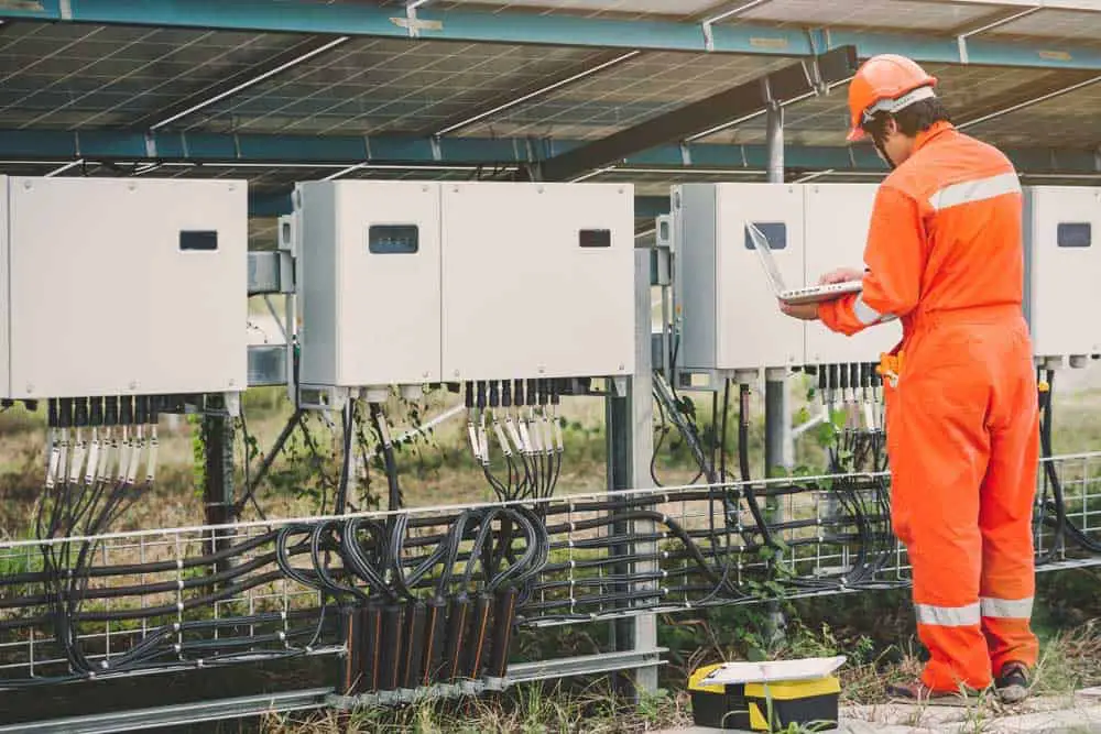 An engineer inspecting string inverters after connecting to them via WiFi