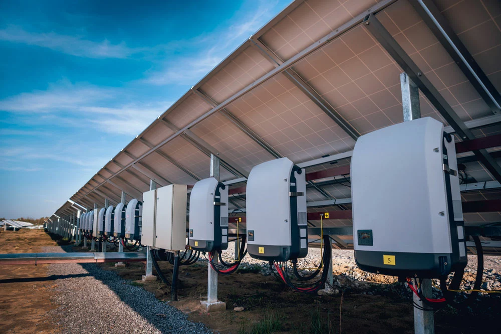 Large inverters installed under solar panels in a solar farm