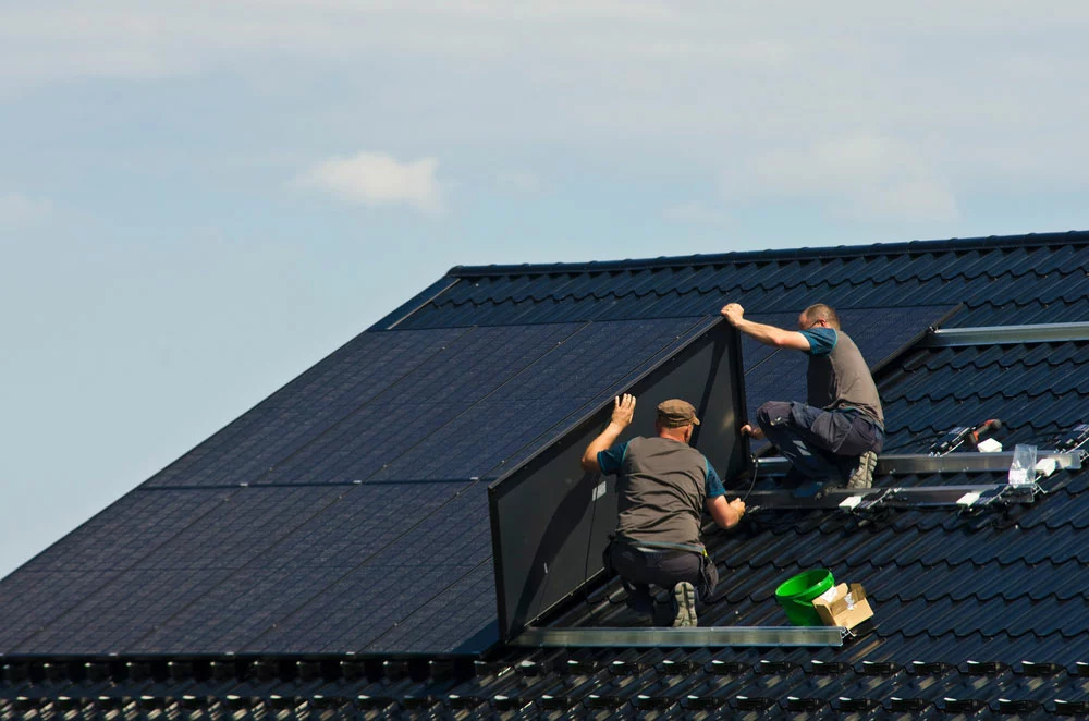 Men installing solar panels on metal roof