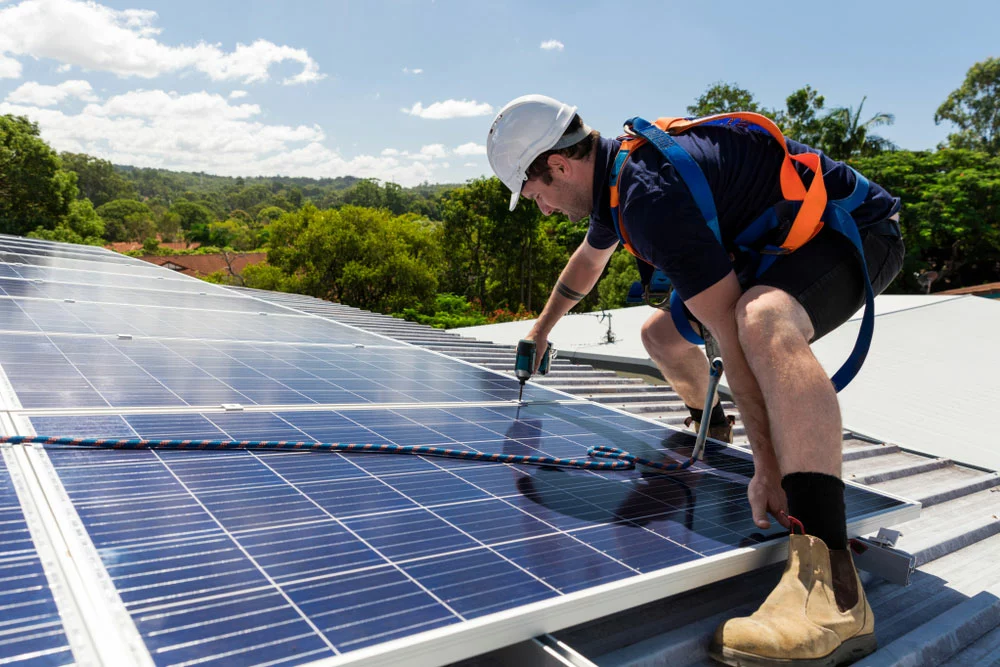 A solar panel technician drill installing a solar on a roof