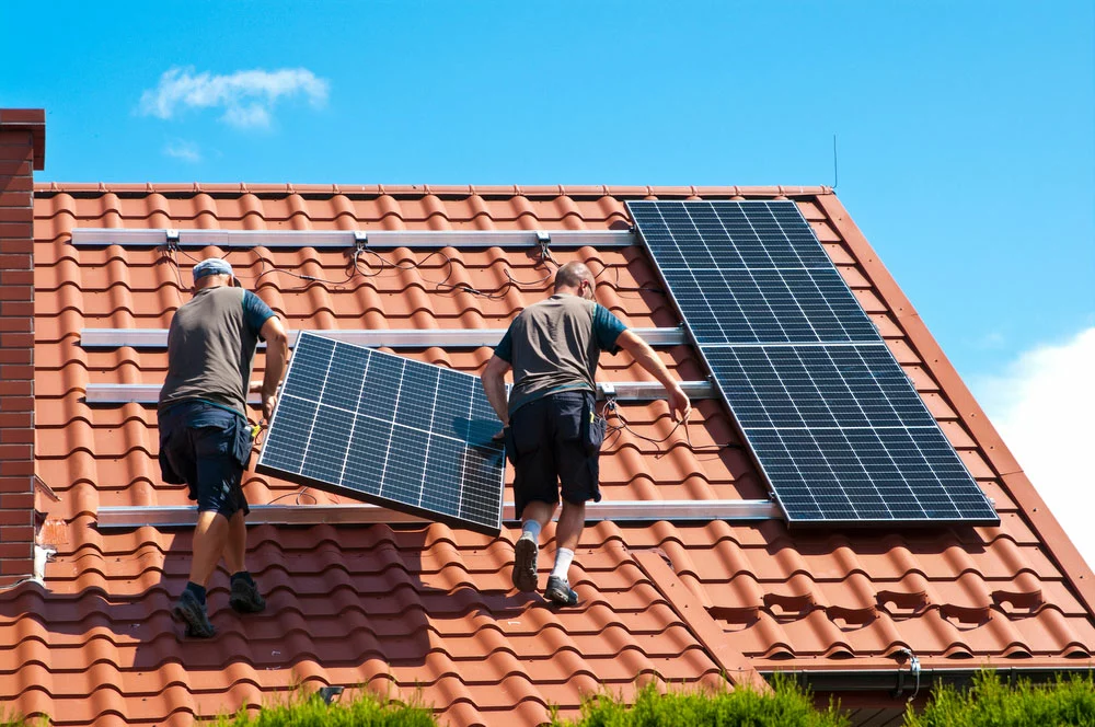 Two men installing solar panels on the roof