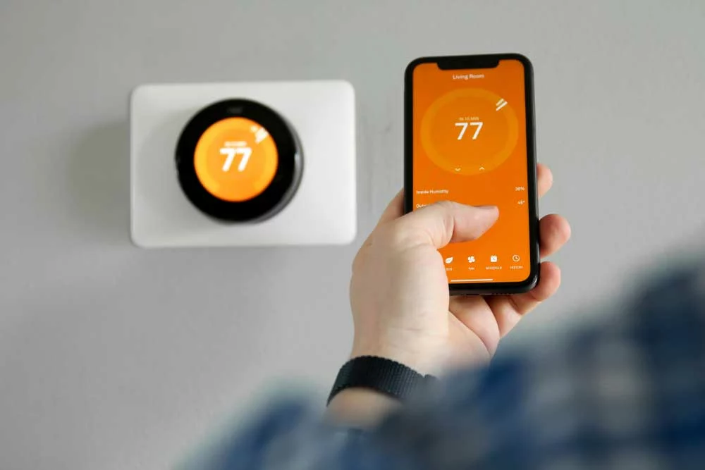A man controlling a smart thermostat