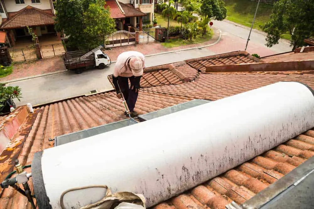 Worker fixing solar water heater on the roof