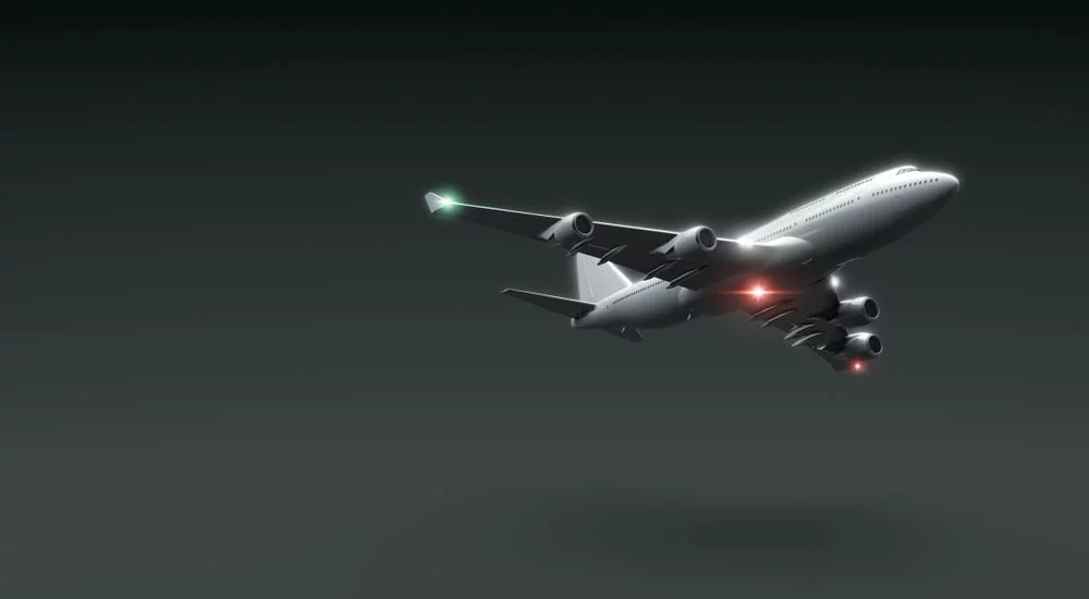 A plane is flying at night with its red beacon light on under the fuselage. Note the green navigation light on the right wing.