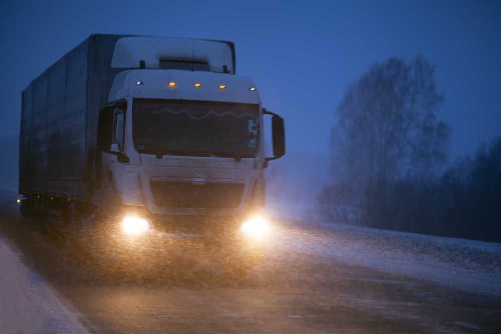 A truck with clearance and marker lights transporting freight in winter