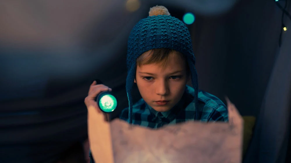 A kid using green light to read a treasure map