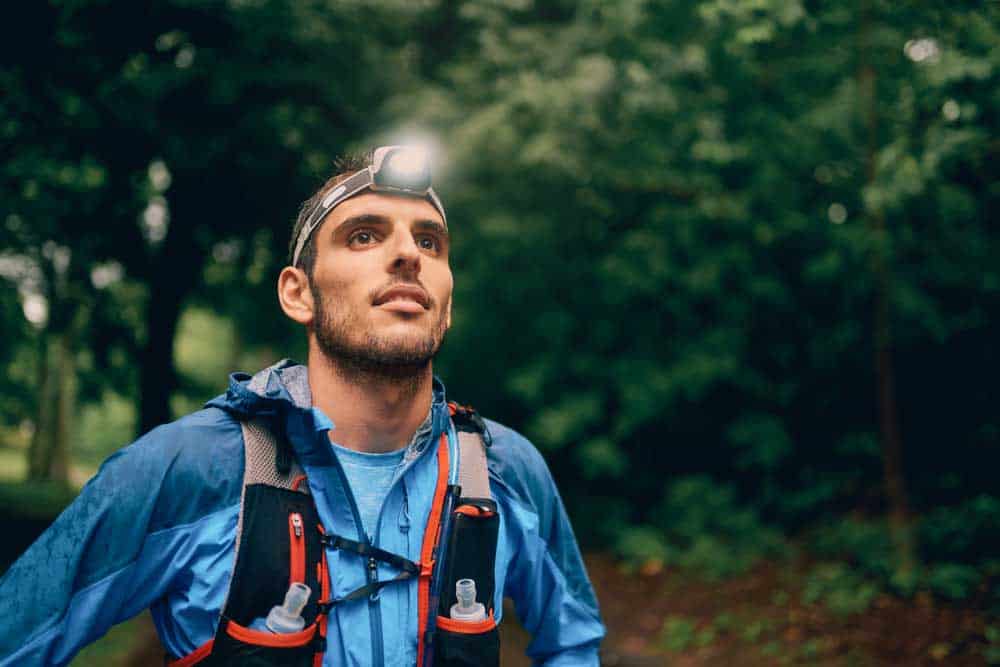Fit male jogger with a headlamp rests during training